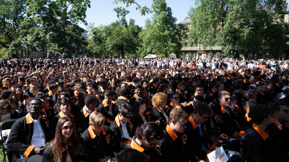Several hundred people sit in a field.