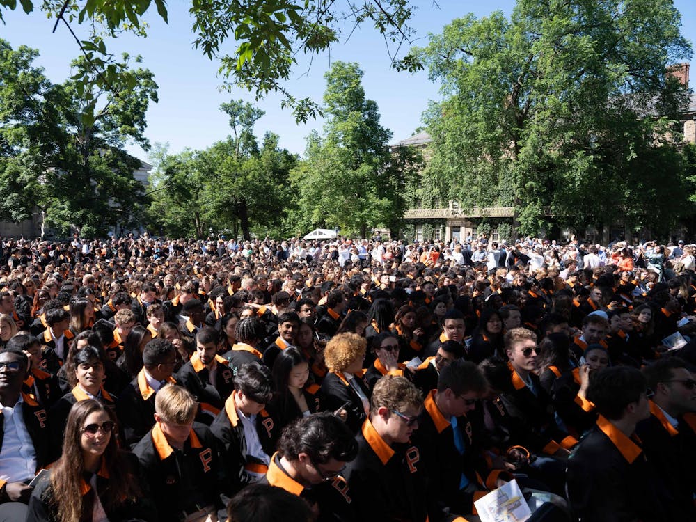 Several hundred people sit in a field.