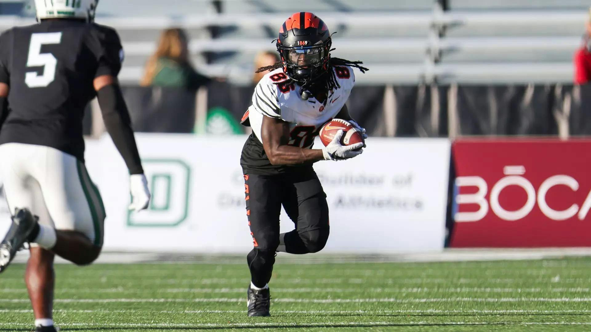A Princeton receiver runs with the football in his hands wearing a white jersey with a black helmet.