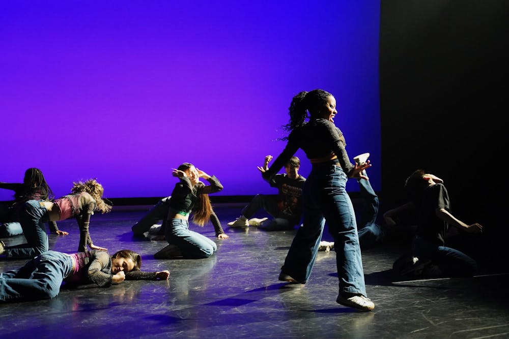 A group of hip-hop dancers on stage with a backdrop of blue light.