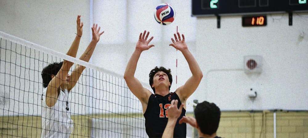 A volleyball player in a black jersey prepares to set a volleyball. 