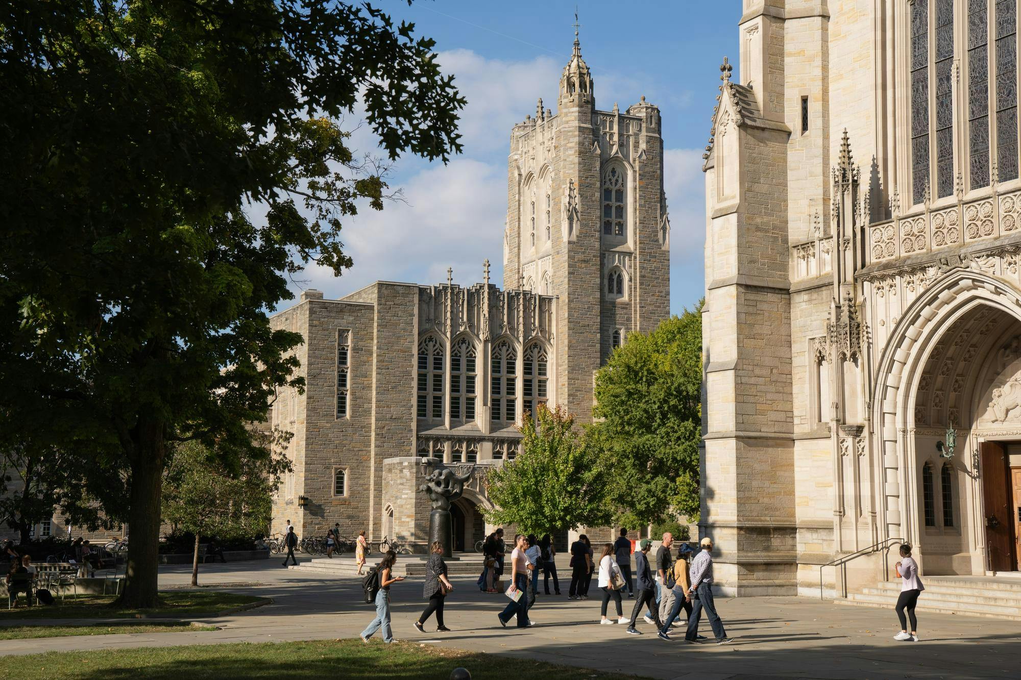 Students walking outdoors in front of two large white buildings.