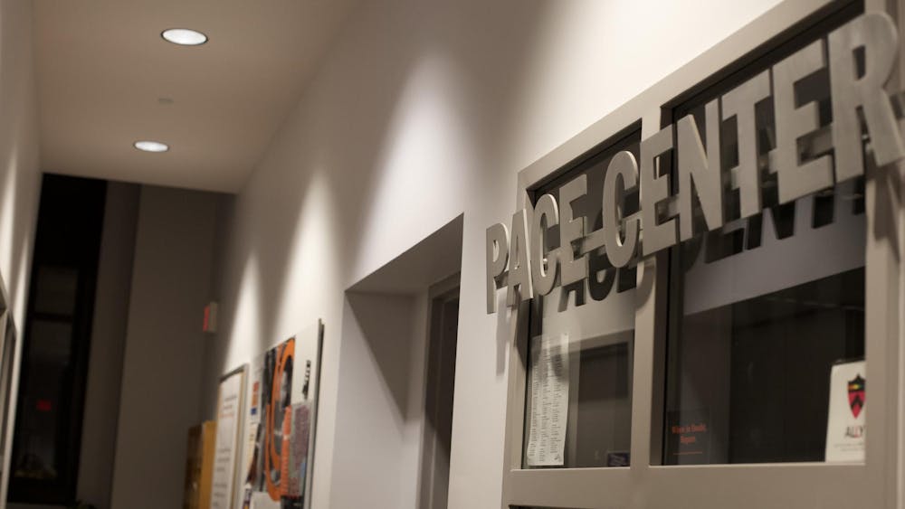 Metal sign reading "Pace Center" above a dorm frame in a dimly lit hall way.