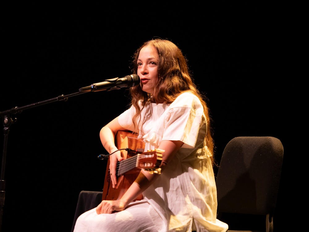 A woman holding a guitar and leaning into a microphone