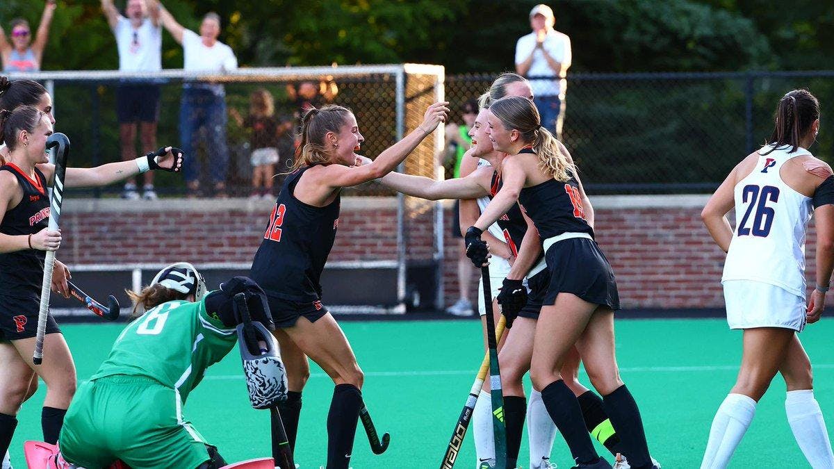 Women in black field hockey jerseys celebrate 