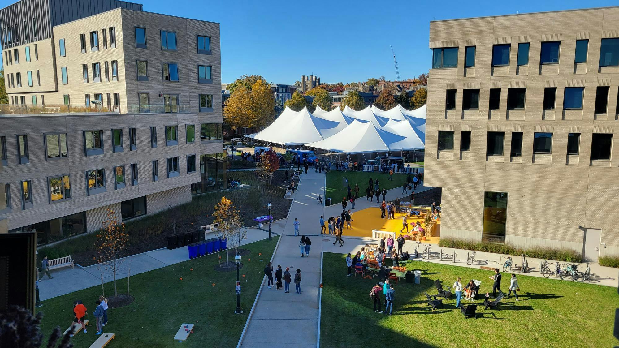 White tents are seen between two modern-looking buildings.