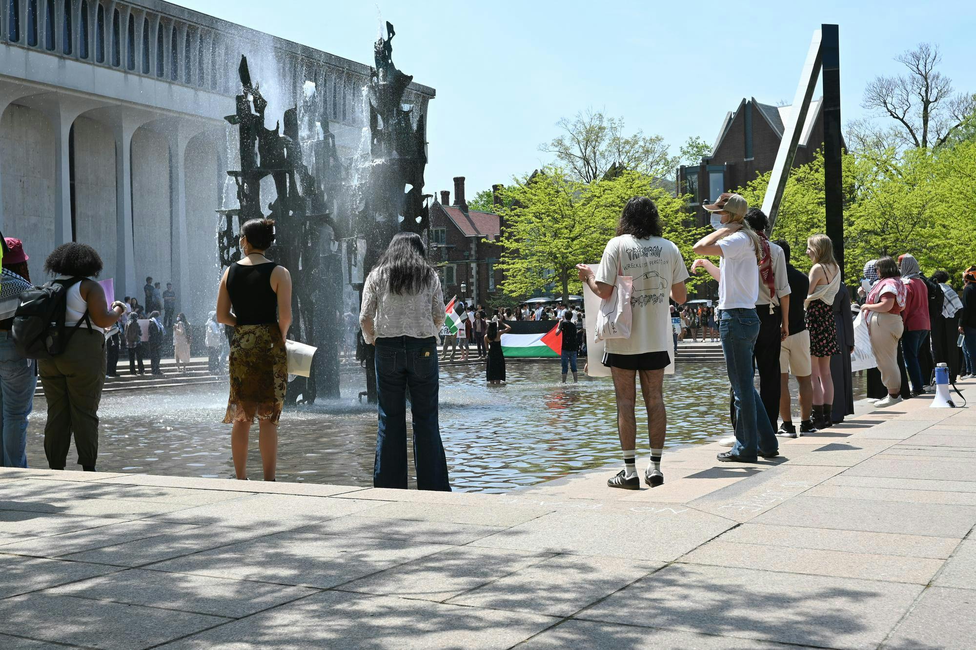 A group of protestors stand in front of a fountain