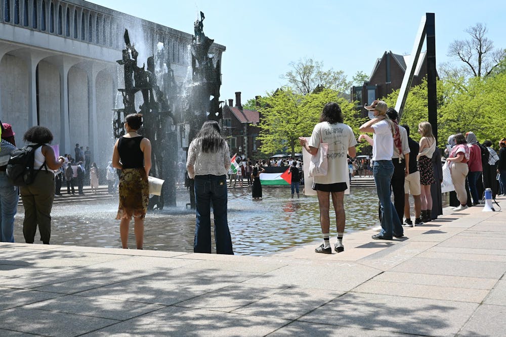 A group of protestors stand in front of a fountain