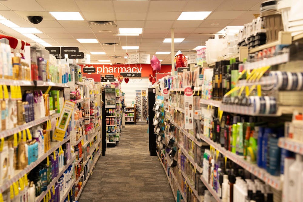 Products line shelves in a store. A red wall reads "pharmacy."