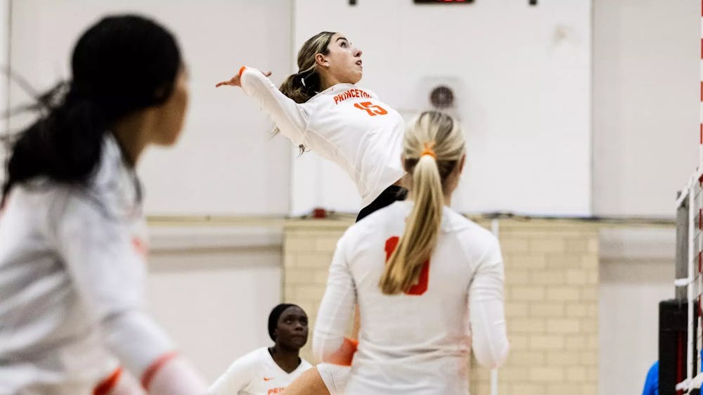Volleyball player in a white jersey rises for a spike.