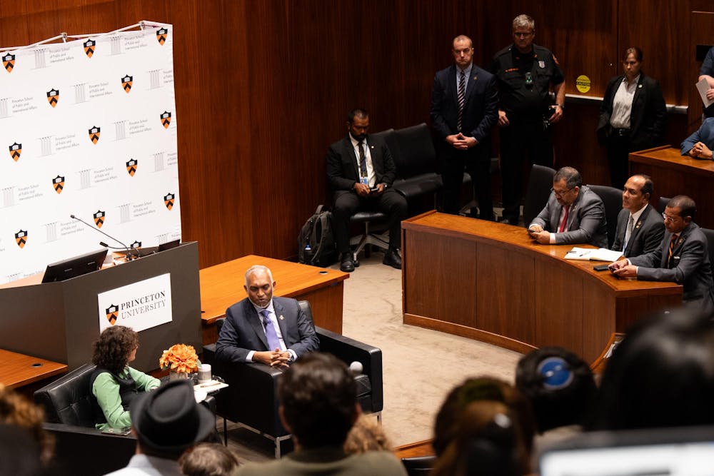 Two people sitting in the center of a room in discussion, with people in raised seats sitting around them.