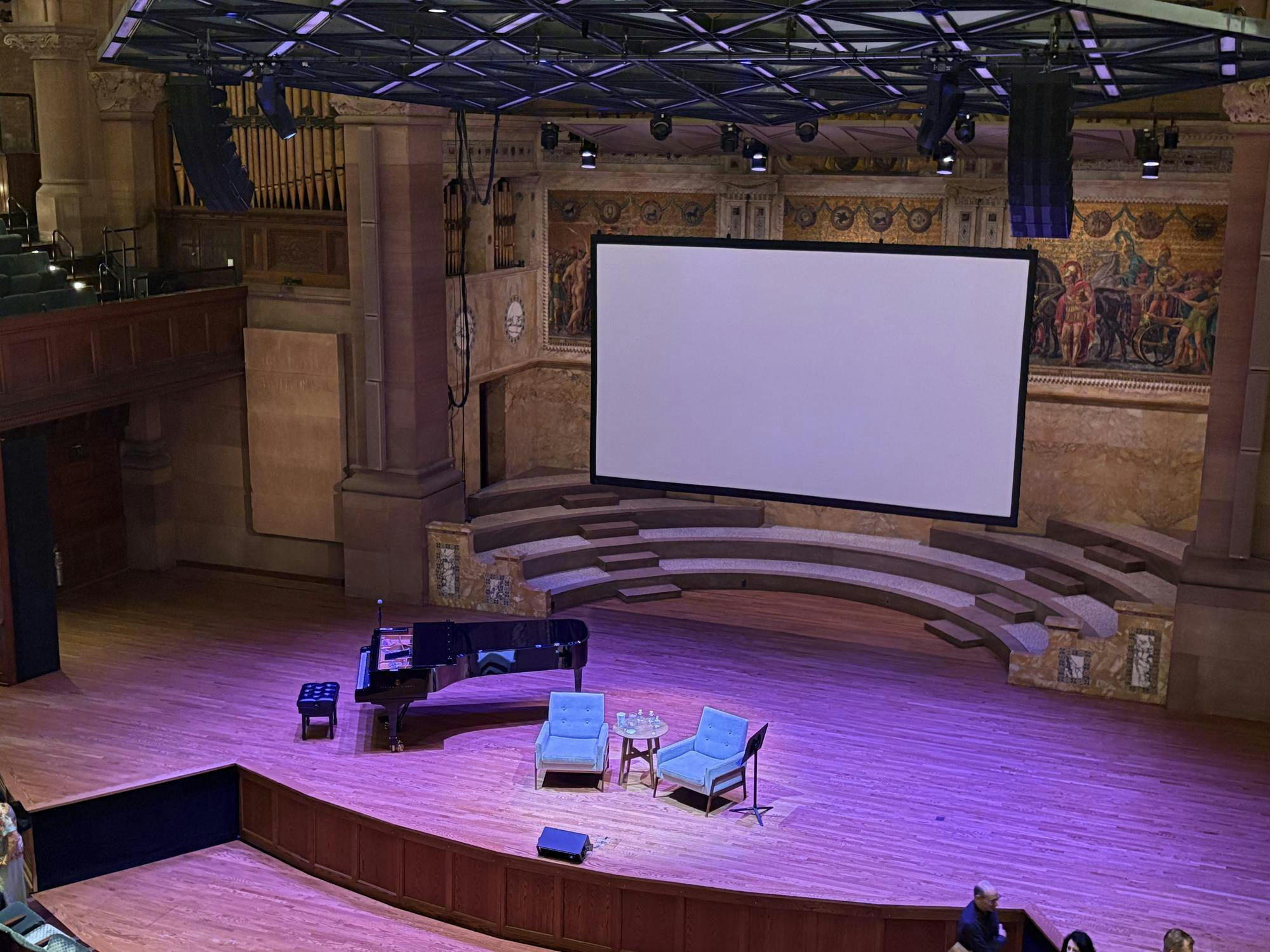 The stage of Richardson Auditorium is cast in purple lighting.