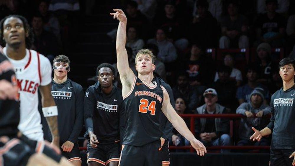 A basketball player shooting the ball holds arm up after a three pointer.