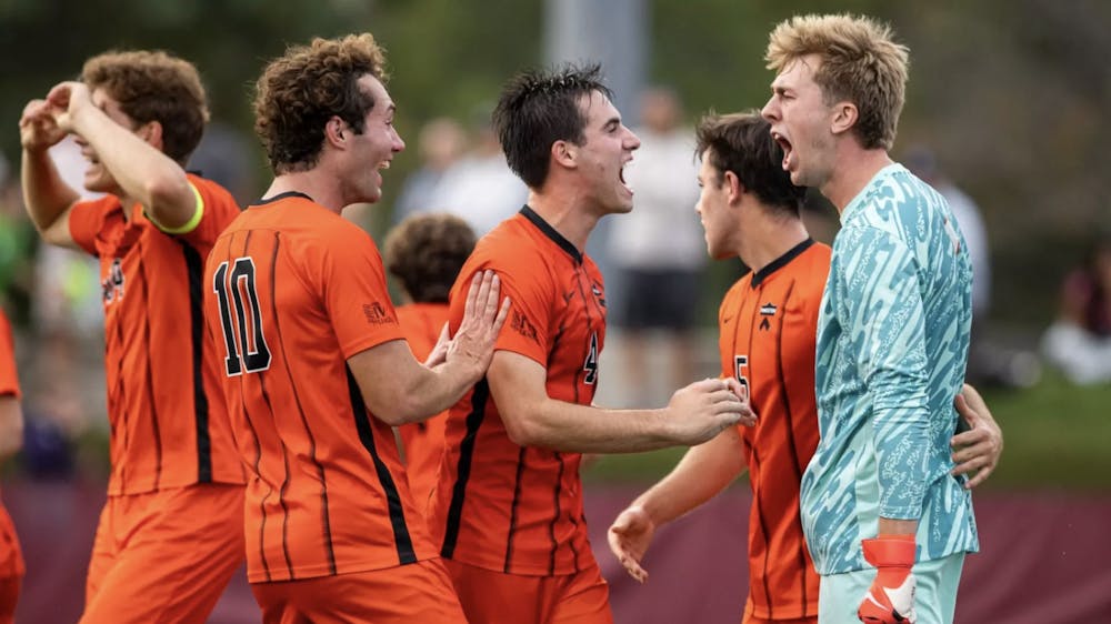 A group of defenders in orange and black jerseys celebrating with the goalkeeper in a blue jersey.