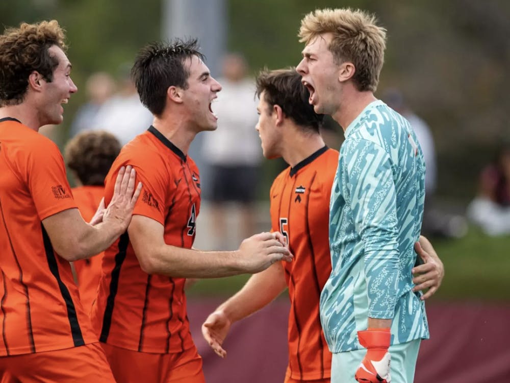 A group of defenders in orange and black jerseys celebrating with the goalkeeper in a blue jersey.