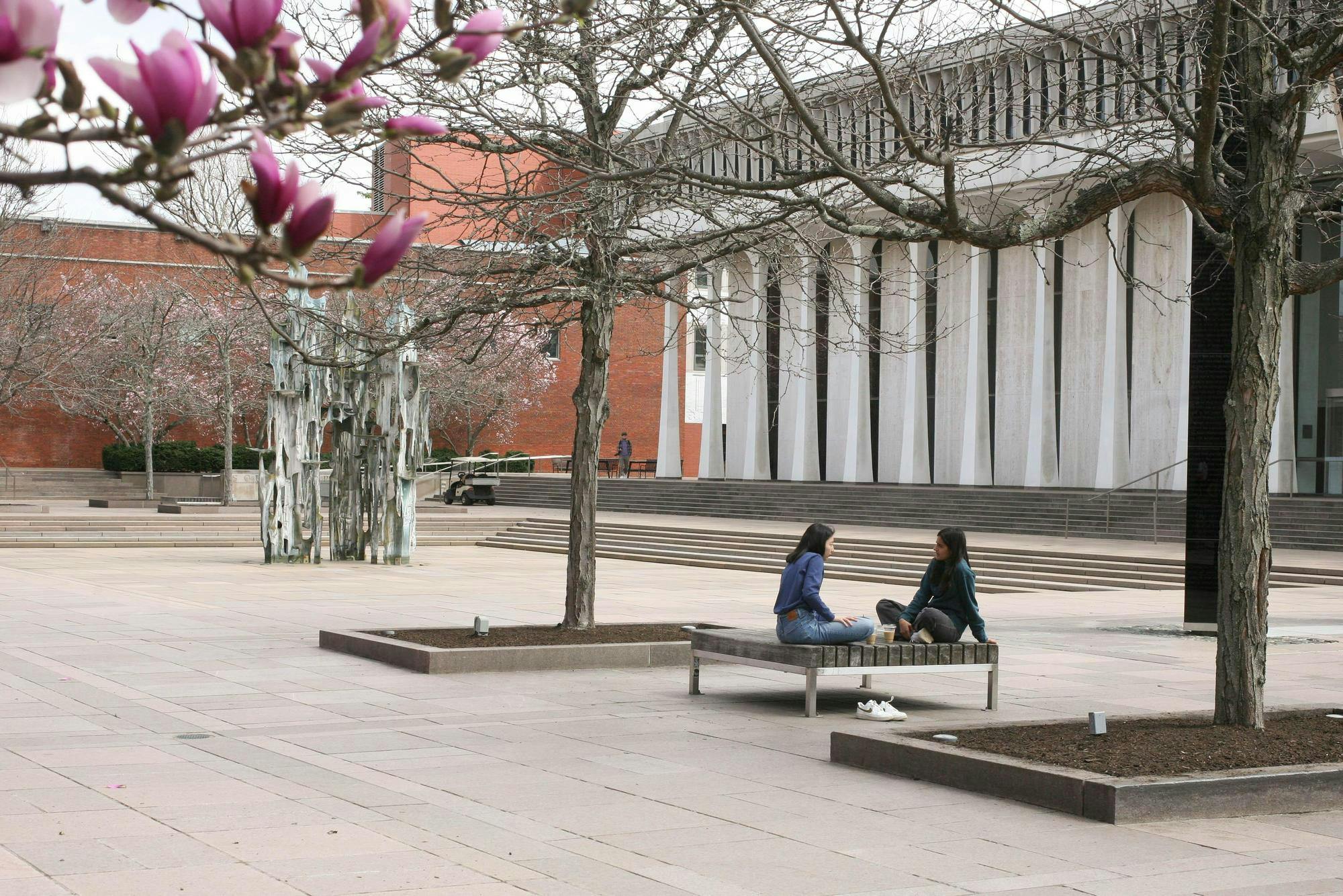 Dos estudiantes platicando en una silla fuera de la facultad de SPIA.