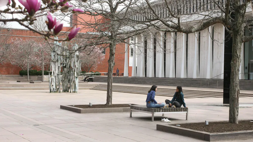 Dos estudiantes platicando en una silla fuera de la facultad de SPIA.