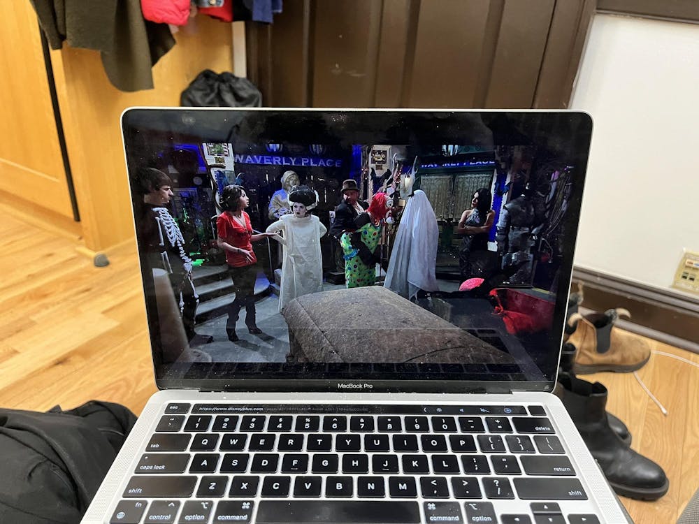 A scene from the Halloween episode of Disney Channel show, "Wizards of Waverly Place" is displayed on a laptop. Characters are dressed in various halloween costumes including a ghost, zombie, and skeleton. 