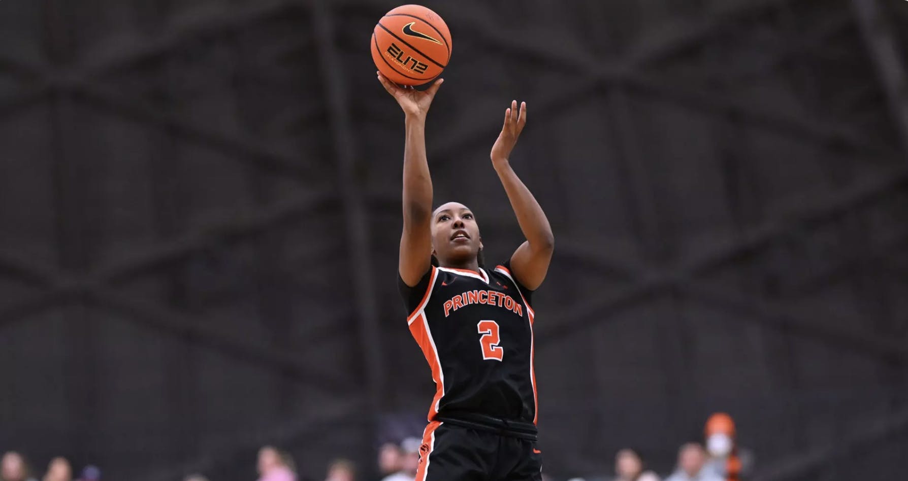 Princeton women's basketball player in orange and black shooting a basketball. 