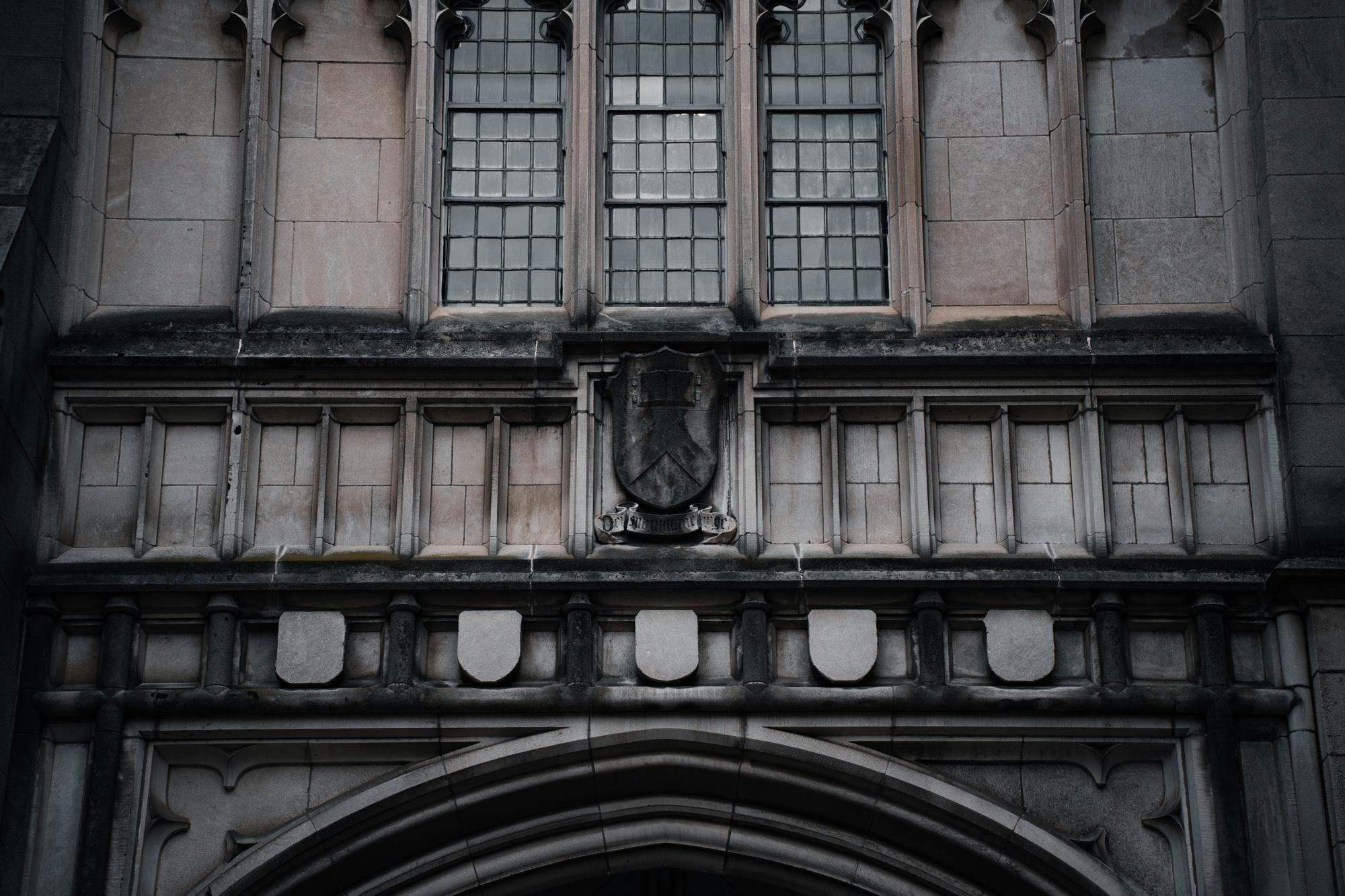 A gray gothic building is dusted with black soot.
