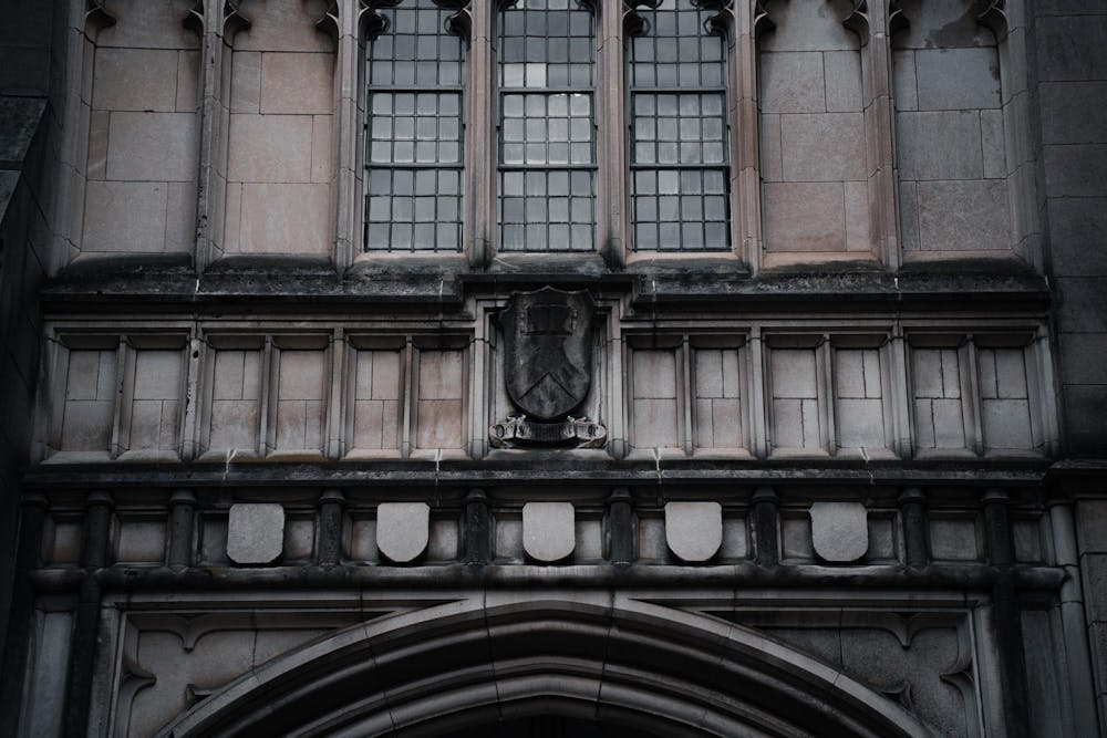 A gray gothic building is dusted with black soot.