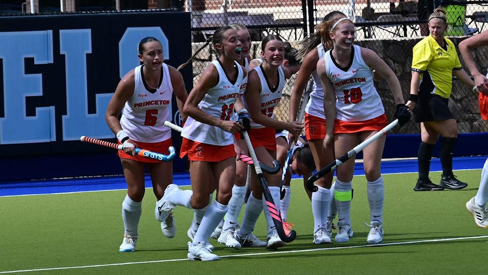 Seven Princeton players in white shirts celebrate after scoring a goal.