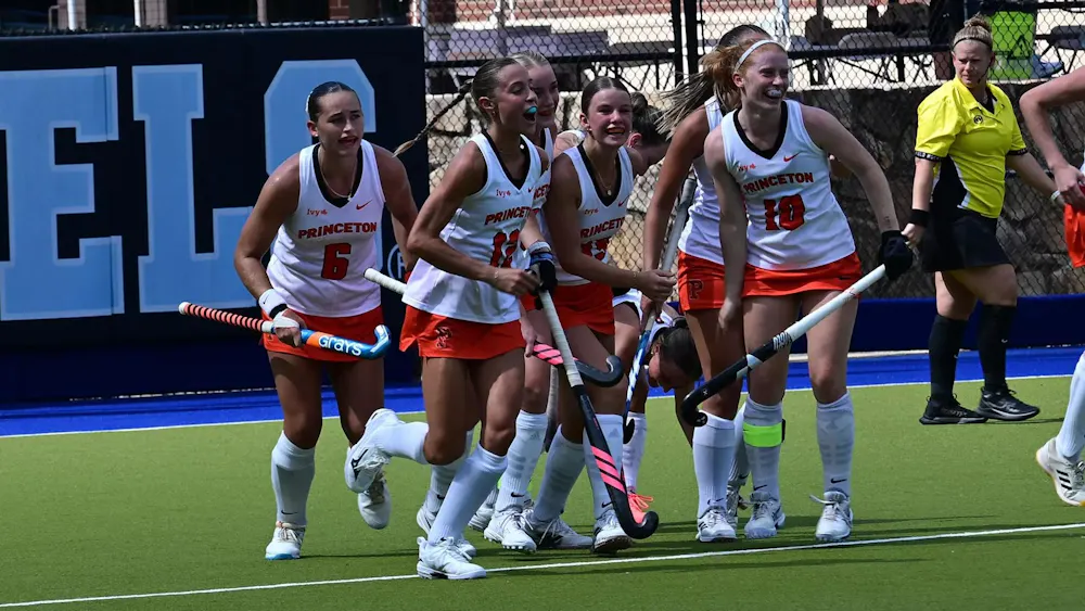 Seven Princeton players in white shirts celebrate after scoring a goal.