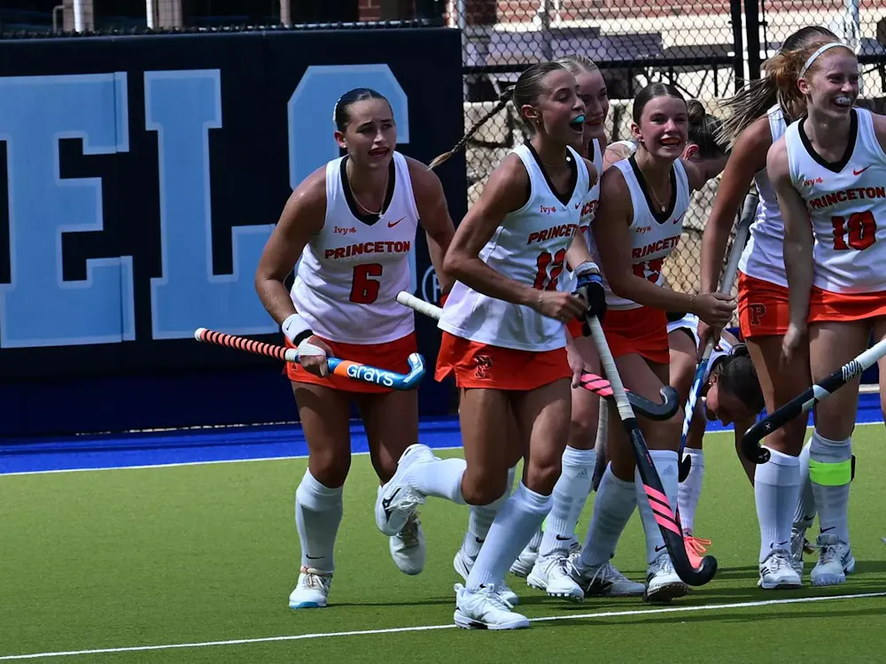 Seven Princeton players in white shirts celebrate after scoring a goal.