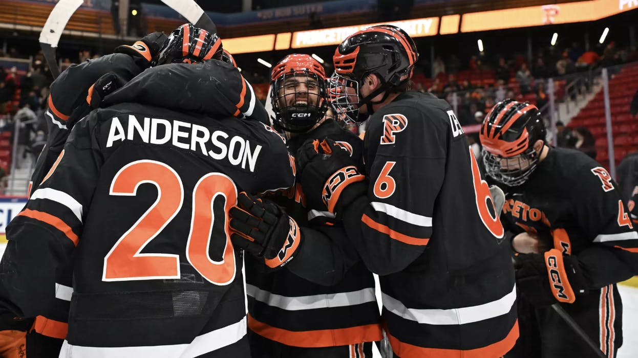 Princeton ice hockey team in a celebratory huddle after beating game win. 
