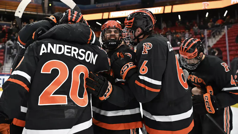 Princeton ice hockey team in a celebratory huddle after beating game win.