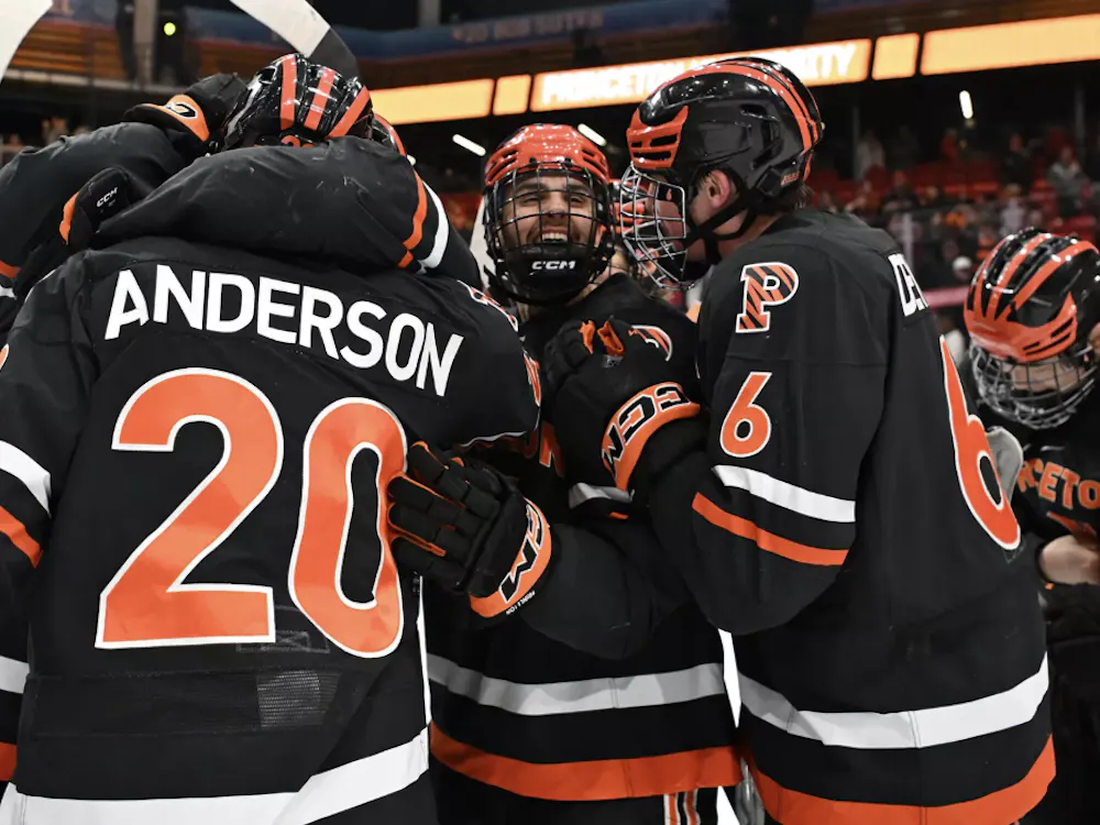 Princeton ice hockey team in a celebratory huddle after beating game win.