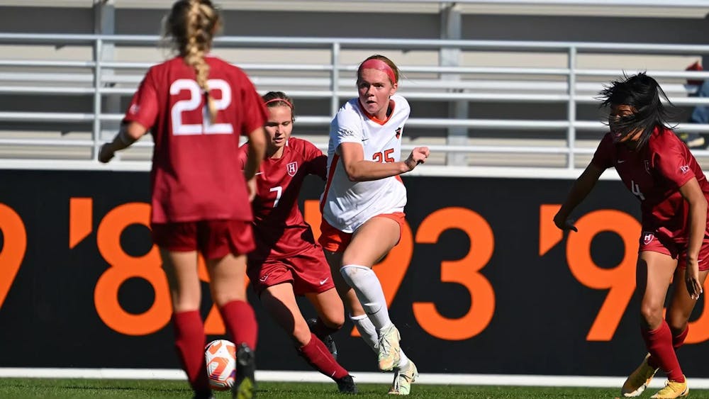 Woman kicks soccer ball surrounded by other players.