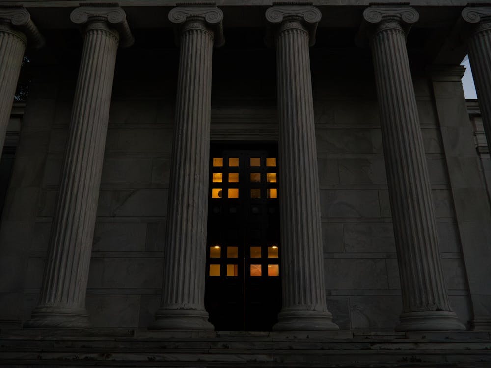 A photo of Whig Hall during dusk, with an orange glow behind the door's windows.