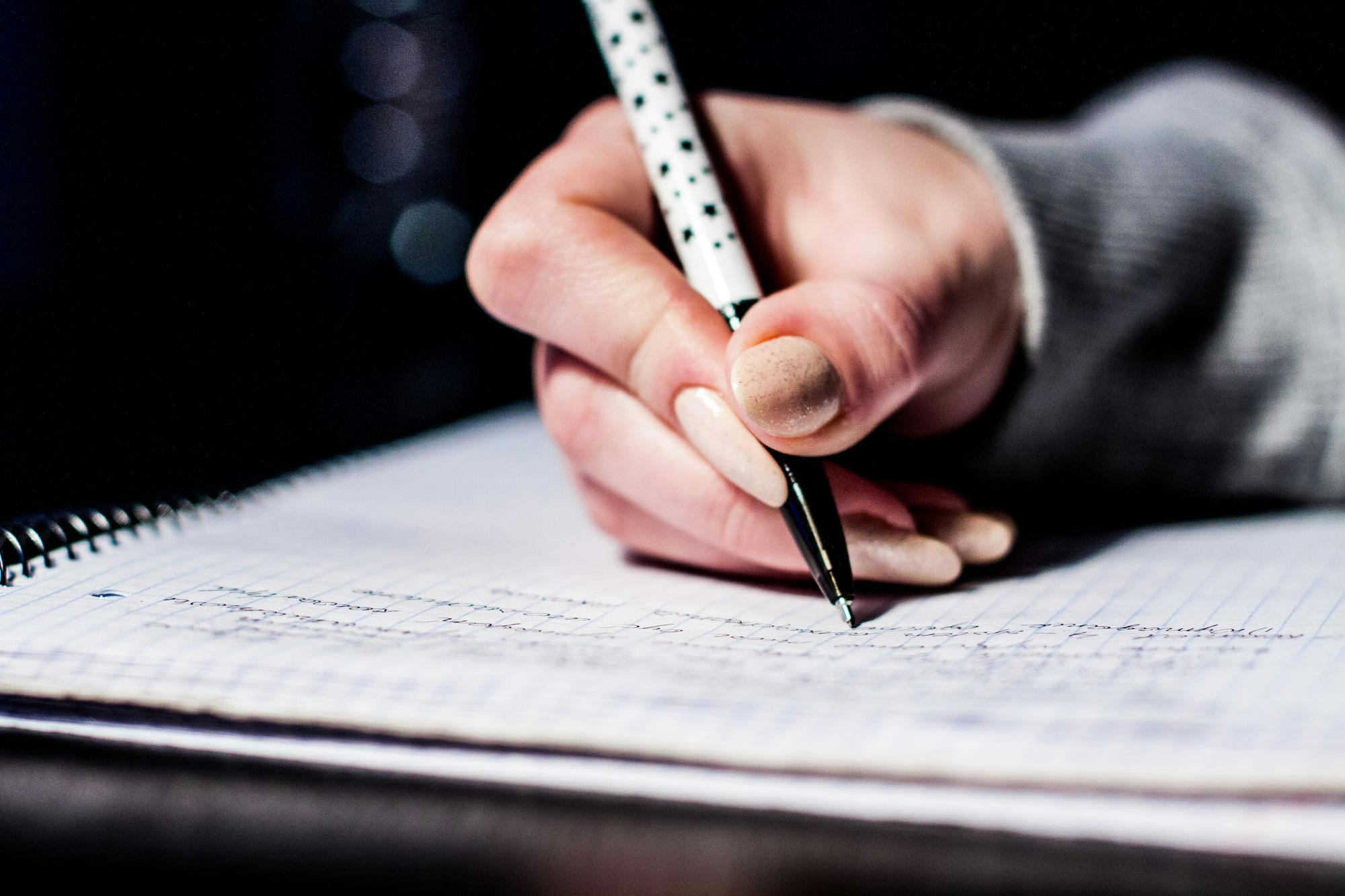 A hand holding a pen on a notebook