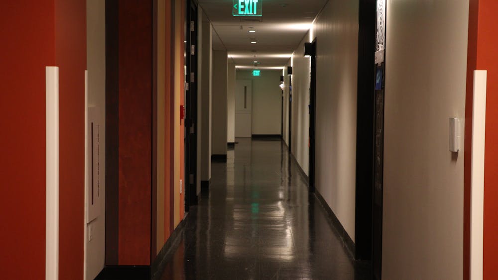 A hallway with red and white walls and grey linoleum floors.