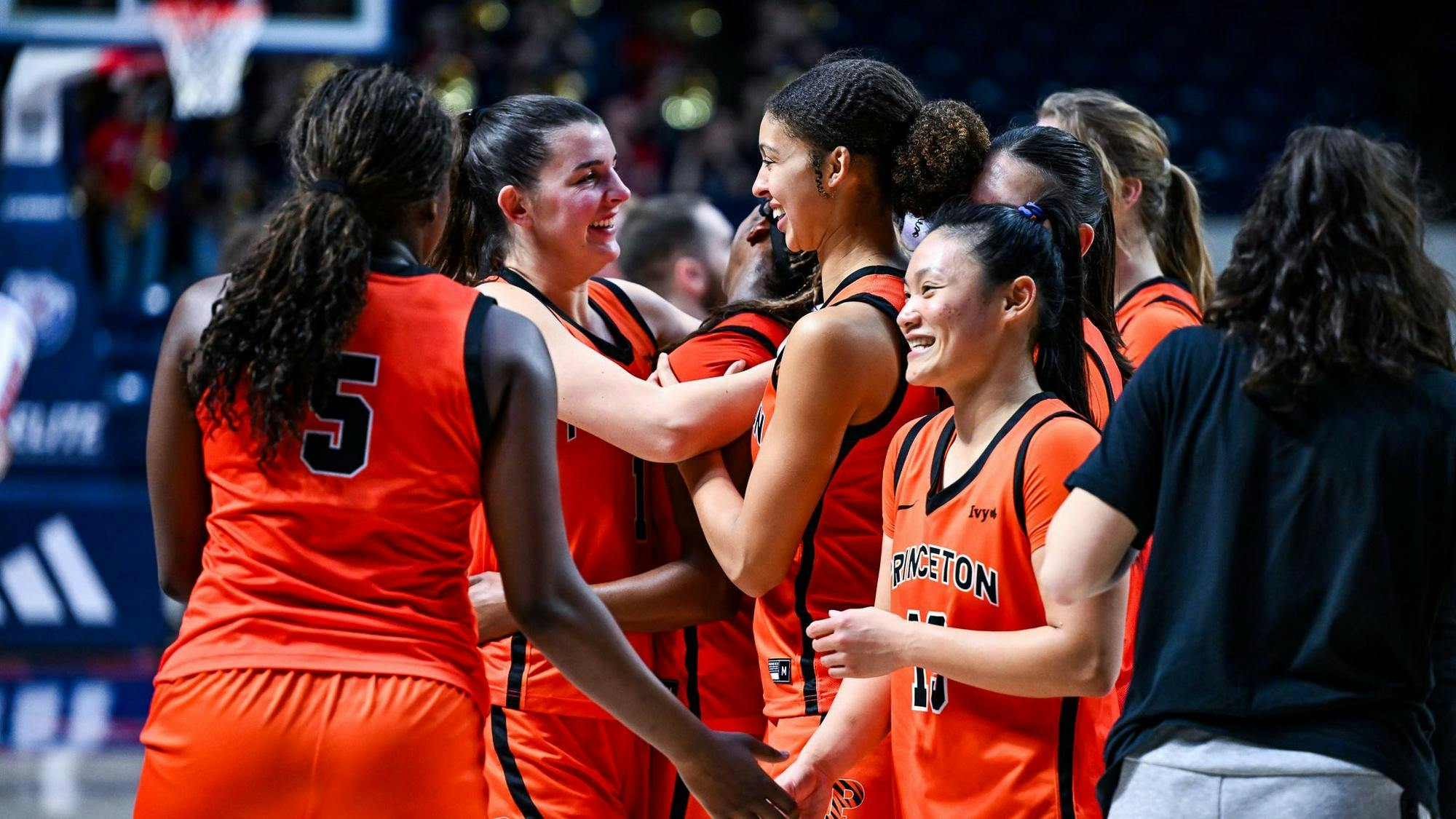 Women in orange and black jerseys celebrate their win together. 