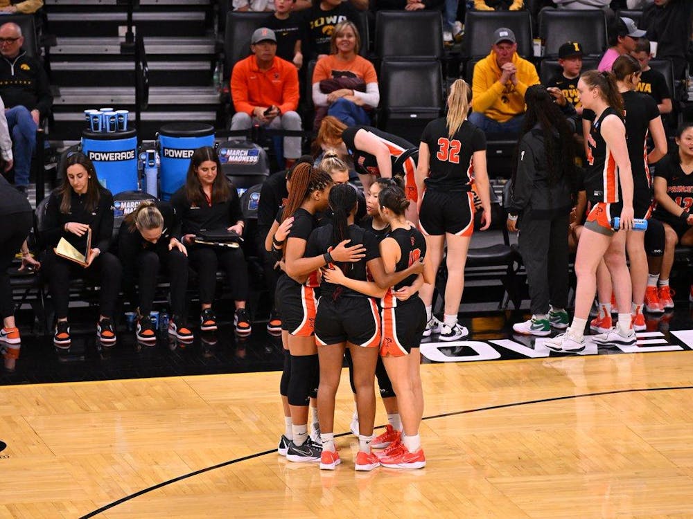 A group of women in black jerseys huddle on basketball court.