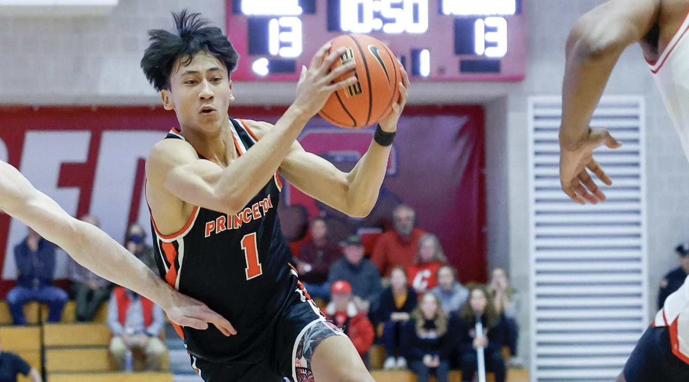 Man wearing black Princeton jersey drives to the basket while holding basketball.