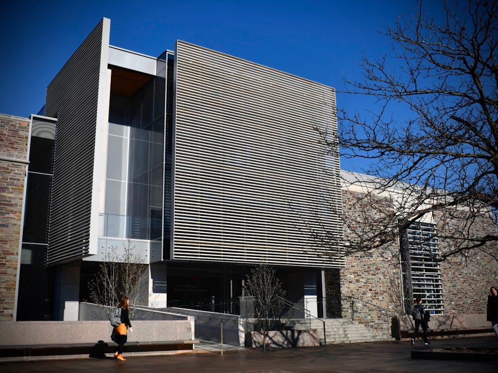 A large gray metallic building stands behind the silhouette of a leafless tree.