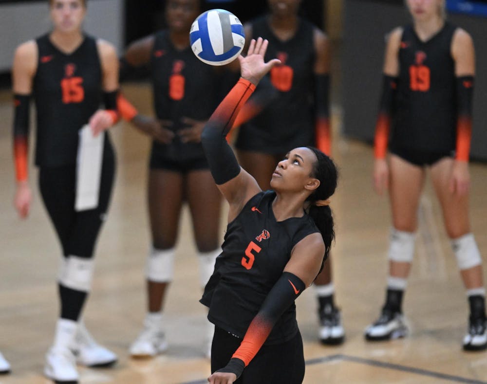 A woman in a black uniform hits a volleyball 