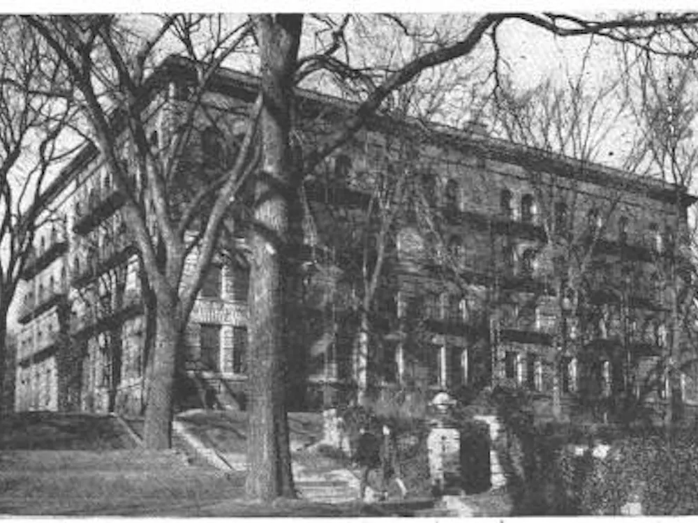 A black and white photograph of the edifice of Brown Hall, a square stone dormitory.