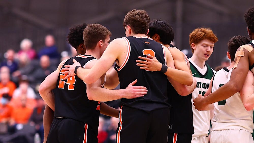 Men's basketball players in black jerseys huddled with their arms around each other.