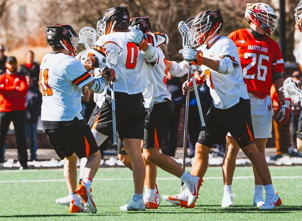 A group of men celebrating on the field after scoring a goal during a lacrosse game.
