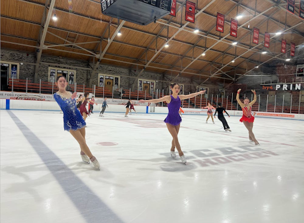 Figure skaters pose in line on ice rink.