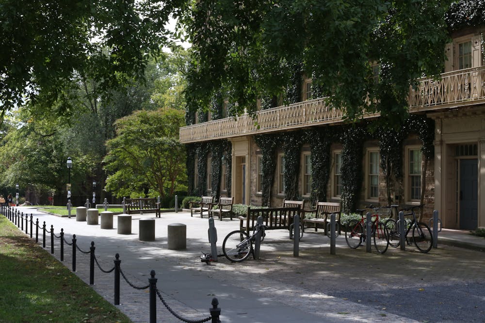 An ivy-covered building with brightly lit benches and a bike rack in front
