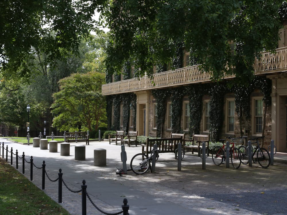The exterior of a building shaded by trees, with bike racks in the foreground.