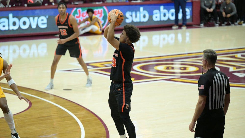 A player in a black jersey jumping and shooting a basketball.