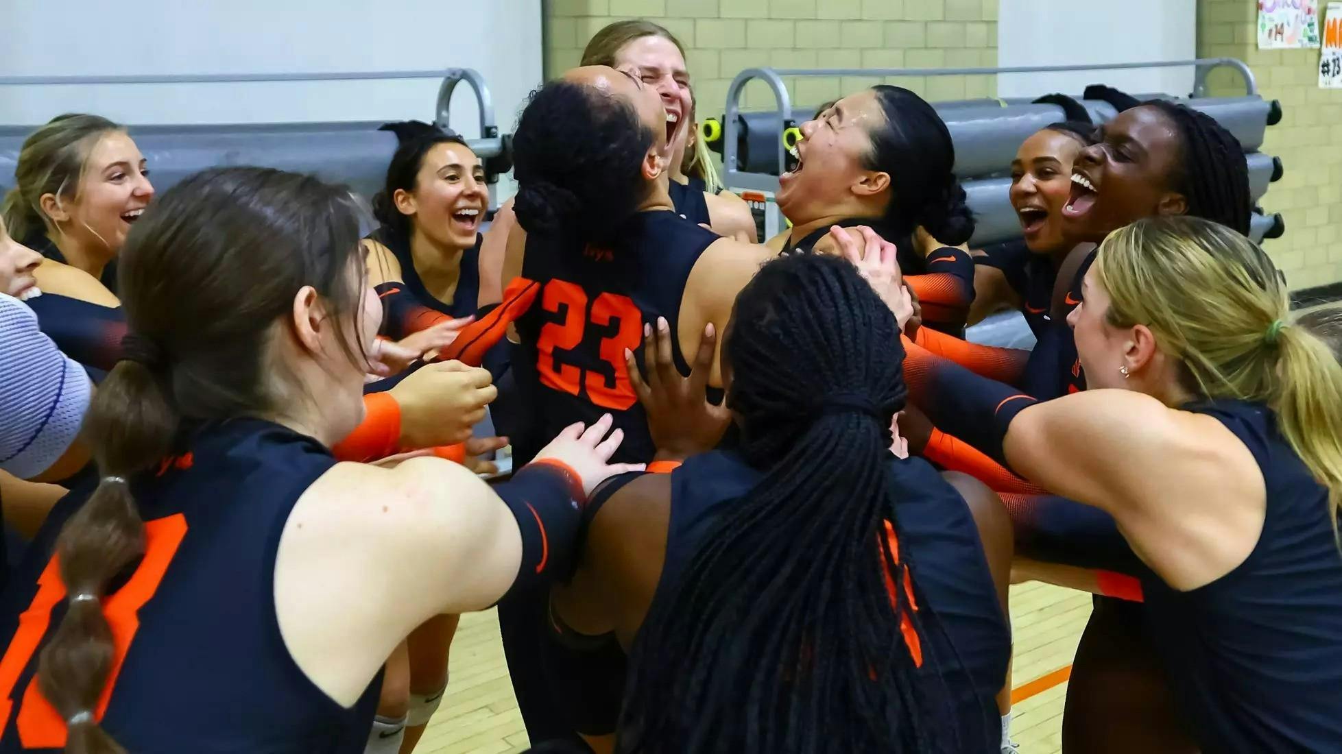 A group of female volleyball players cheering with one another courtside. 