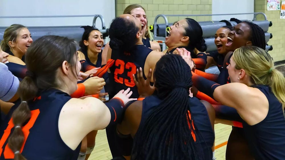 A group of female volleyball players cheering with one another courtside. 