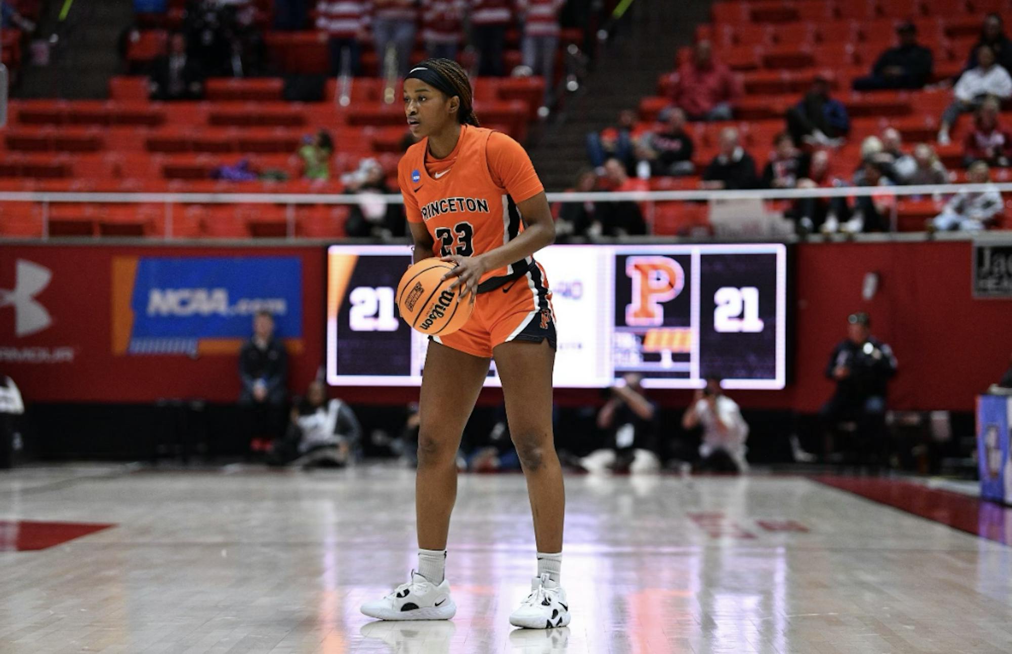 Woman in orange jersey holds basketball.